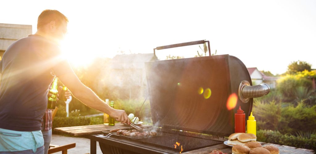 Young handsome men roasting barbecue on grill in cottage countryside. Copy space.